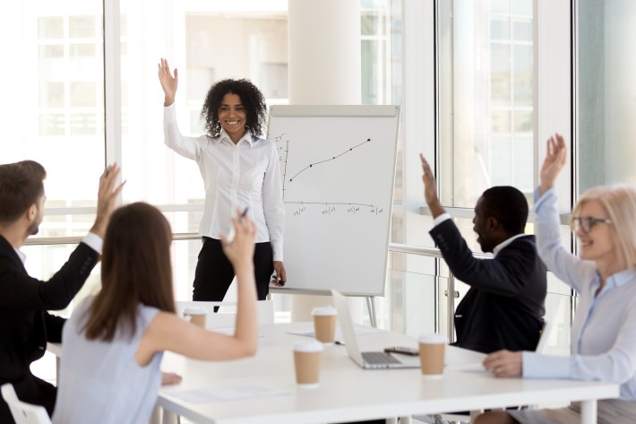 Smiling African-american Coach Raising Hand With Team Voting At
