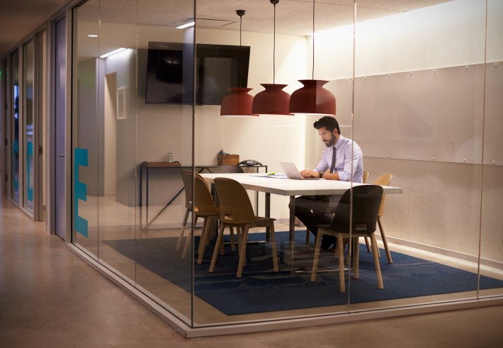 Hispanic businessman works in cubicle at corporate business