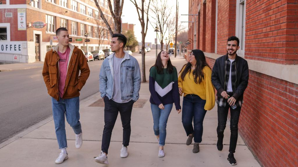 Five young people walking down the street together